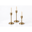 Three metal candle holders shown holding white taper candles; candles are styling props and inclusion is unconfirmed.